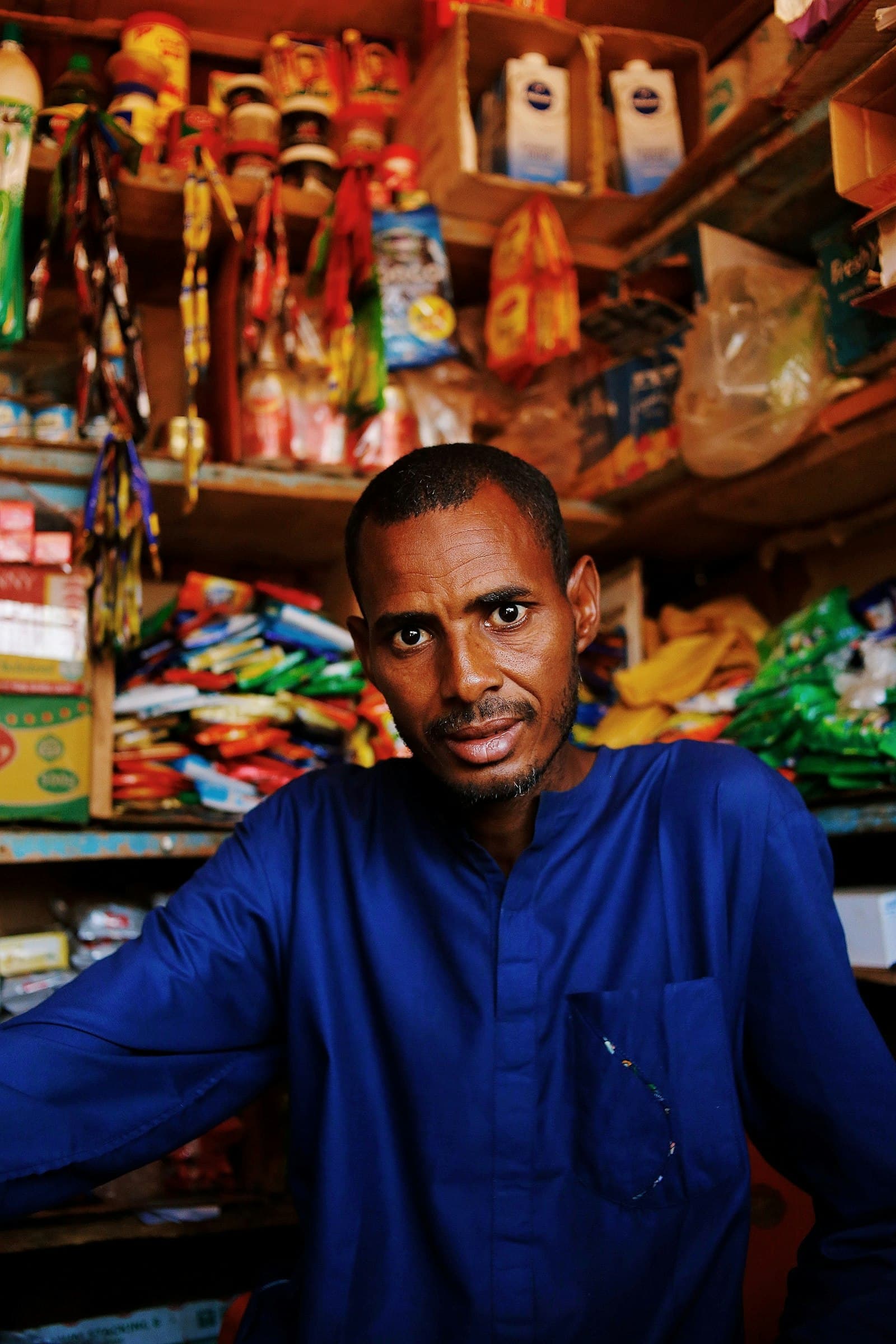 A kiosk owner standing in his fully stocked shop