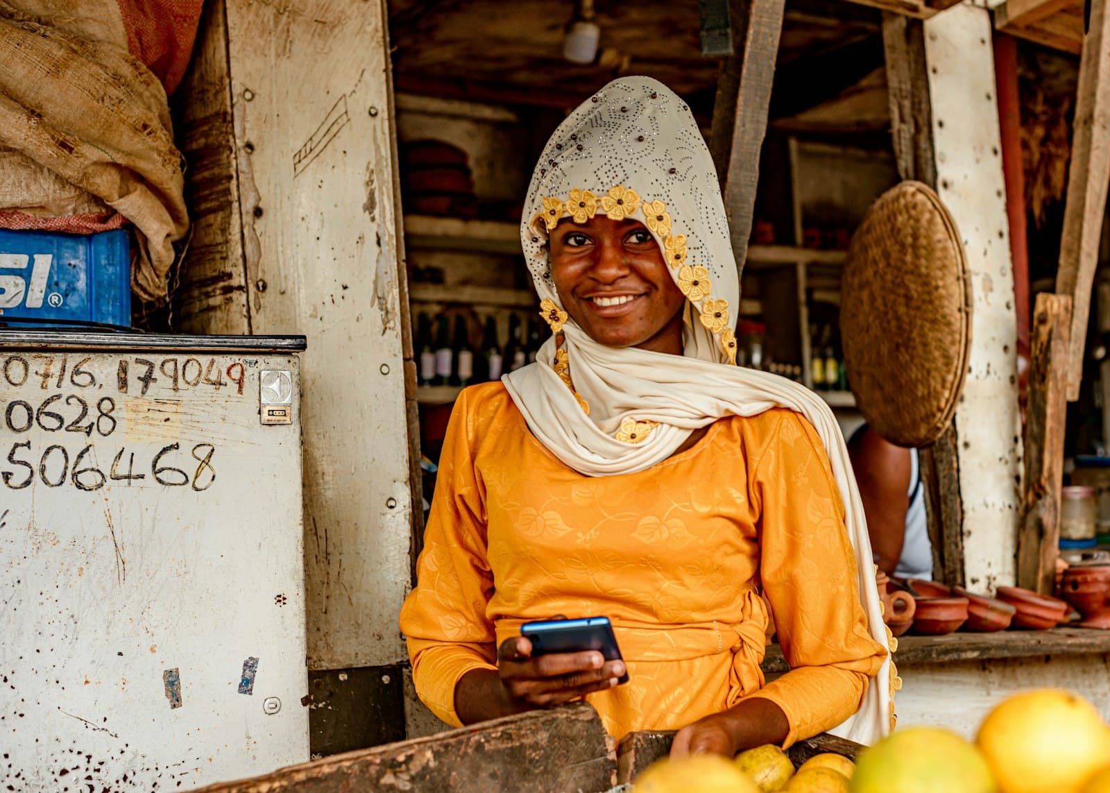 A trader at her market stall holding a phone